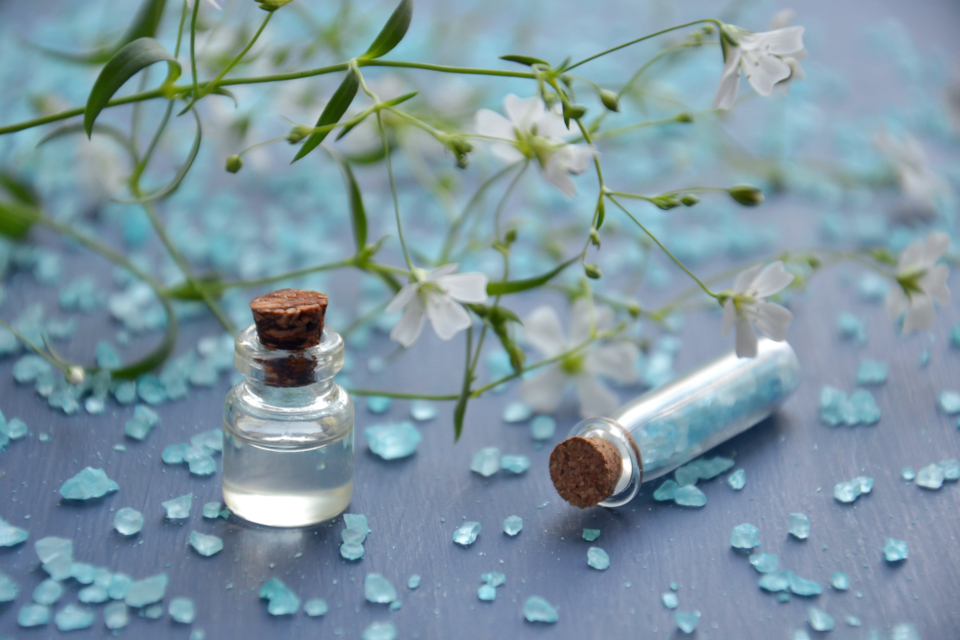 Frascos de aceite esencial, sal de baño y flores blancas sobre una superficie, en un ambiente de bienestar